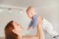 Mother playing with his infant son, holding him in her hands above her head, looks like fly Royalty Free Stock Photo