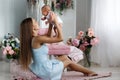 Mother playing with newborn baby sitting on the floor Royalty Free Stock Photo