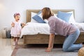 Mother is playing peek a boo or hide and seek with her little baby toddler in the bedroom while the girl is laughing in happiness Royalty Free Stock Photo