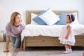 Mother is playing peek a boo or hide and seek with her little baby toddler in the bedroom while the girl is laughing in happiness Royalty Free Stock Photo