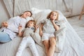 Mother playing with siblings in the morning on bed. Happy family with two child boys Royalty Free Stock Photo