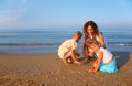 Mother plays with children finding shells on sand Royalty Free Stock Photo