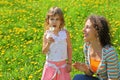 Mother plays with girl which breath on dandelion Royalty Free Stock Photo