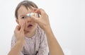 Mother pouring eye drops in the eye of her daughter