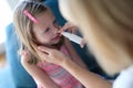 Mother puffing little girl nose with antibacterial drops at home