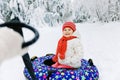 Mother pull little toddler girl on snow tube. Cute little happy child having fun outdoors in winter on colorful tire