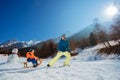 Mother pull uphill a boy on the wooden sledge at winter