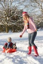 Mother Pulling Son On Sledge Through Snowy Landsca Royalty Free Stock Photo