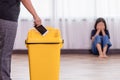 Mother punishing her daughter with throwing smartphone into yellow trash Royalty Free Stock Photo