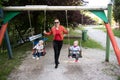 Mother Pushing Her Baby`s Having Fun on Swing Royalty Free Stock Photo