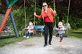 Mother Pushing Her Baby`s Having Fun on Swing Royalty Free Stock Photo