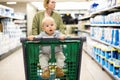 Mother pushing shopping cart with her infant baby boy child down department aisle in supermarket grocery store. Shopping Royalty Free Stock Photo