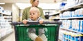 Mother pushing shopping cart with her infant baby boy child down department aisle in supermarket grocery store. Shopping Royalty Free Stock Photo