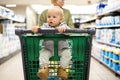 Mother pushing shopping cart with her infant baby boy child down department aisle in supermarket grocery store. Shopping Royalty Free Stock Photo