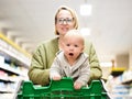 Mother pushing shopping cart with her infant baby boy child down department aisle in supermarket grocery store. Shopping Royalty Free Stock Photo