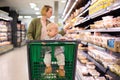 Mother pushing shopping cart with her infant baby boy child down department aisle in supermarket grocery store. Shopping Royalty Free Stock Photo