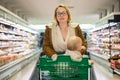 Mother pushing shopping cart with her infant baby boy child down department aisle in supermarket grocery store. Shopping Royalty Free Stock Photo