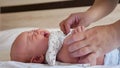 Mother puts bodysuit on crying baby girl lying on bed Royalty Free Stock Photo