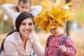 Mother puts yellow fallen leaves on son head. Happy family is in autumn city park. Children and parents. They posing, smiling, pla Royalty Free Stock Photo