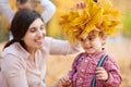 Mother puts yellow fallen leaves on son head. Happy family is in autumn city park. Children and parents. They posing, smiling, pla Royalty Free Stock Photo