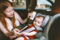 Mother putting baby in safety car seat mom and child together family Royalty Free Stock Photo