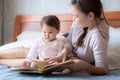 Mother reading a book to her child on the bed. Bedtime story. Learning how to read. Royalty Free Stock Photo