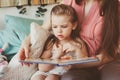 Mother reading book to toddler daughter in bedroom for good night. Casual lifestyle capture of happy family