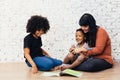 Mother reading a fairy tale fable story for kids at home. African American happy family concept.