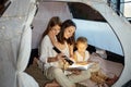 Mother reads a book of fairy tales for her children while sitting in a tent at night. Mom son and daughter reading a book with Royalty Free Stock Photo