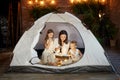 Mother reads a book of fairy tales for her children while sitting in a tent at night. Mom son and daughter reading a book with a Royalty Free Stock Photo