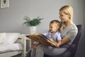 Mother reads a children's book to her little toddler son sitting in a chair in a cozy bedroom. Royalty Free Stock Photo