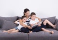 Mother reads an interesting book with her sons of the sofa. Royalty Free Stock Photo