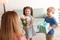 Mother receiving gift and flowers from her cute little children at home Royalty Free Stock Photo