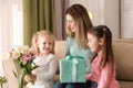 Mother receiving gift and flowers from her cute little daughters at home Royalty Free Stock Photo