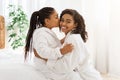 Mother`s Day. Adorable Black Little Girl Kissing Mom At Home, Wearing Bathrobes Royalty Free Stock Photo