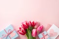 Top view photo of bunch of pink tulips blue gift boxes envelope and letter with heart on isolated pastel pink background Royalty Free Stock Photo