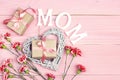 Mother`s Day background with carnation flowers and gift boxes on pink wooden table