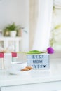 Mother`s day background. Morning suprise - cup of tea with cookies, gift box, lightbox with words Best mom ever and tulip flower