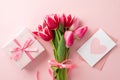 Top view photo of bouquet of pink tulips giftbox with ribbon bow and envelope with postcard on pastel pink background Royalty Free Stock Photo