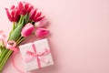 Top view photo of giftbox with ribbon bow and bouquet of pink tulips on isolated pastel pink background with copyspace Royalty Free Stock Photo