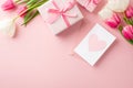 Top view photo of present boxes with ribbon bows envelope postcard with heart and bunches of pink and white tulips