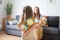 Mother`s day. child gives her mom flower made of paper. baby girl. girl hides craft in her hands