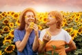 Mother`s Day concept. Senior mother and her daughter doing manicure and make-up out of petals in sunflower field Royalty Free Stock Photo