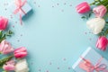 Top view photo of white and pink tulips blue present boxes with ribbon bows and sprinkles on pastel blue background Royalty Free Stock Photo