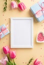 Top view vertical photo of photo frame pink tulips blue gift boxes with ribbon bows and heart shaped saucer with sprinkles Royalty Free Stock Photo