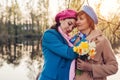 Mother`s day. Daughter giving her senior mother bouquet of flowers. Family walking in spring park by river hugging Royalty Free Stock Photo