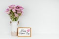 Decor with mum flowers and Happy Mothers Day sign on a white shelf against a white wall background