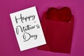 Mother\'s Day decorations concept. Top view photo of white invitation card with heart shape cushion toy on pink.