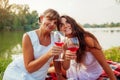 Mother`s day. Mother drinking wine with her adult daughter in spring park. Family having picnic outdoors Royalty Free Stock Photo