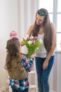 Mother's Day - Girl gives her mom a big bouquet of tulips, touching
